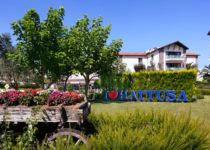 Tesisin bahçesindeki Hattuşa tabelası ve çiçekli oturma alanı
